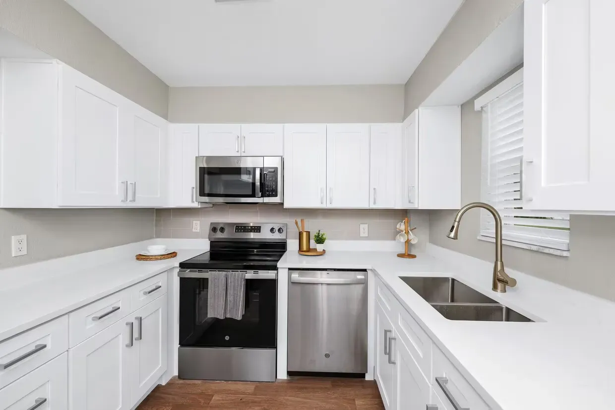 White kitchen with stainless steel appliances and countertops.