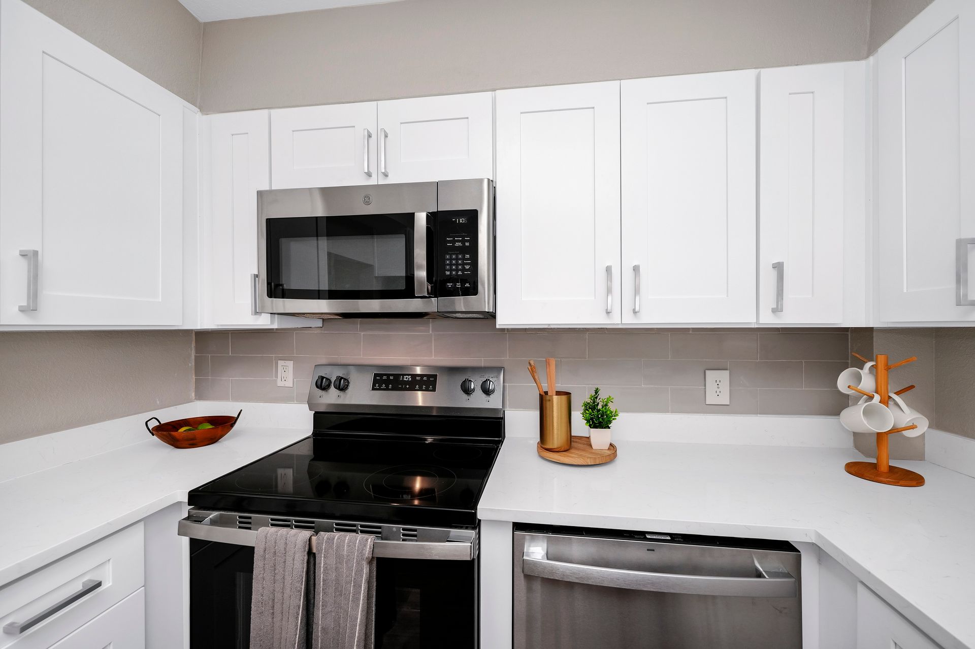 White kitchen with stainless steel appliances, white cabinets, and light countertops.