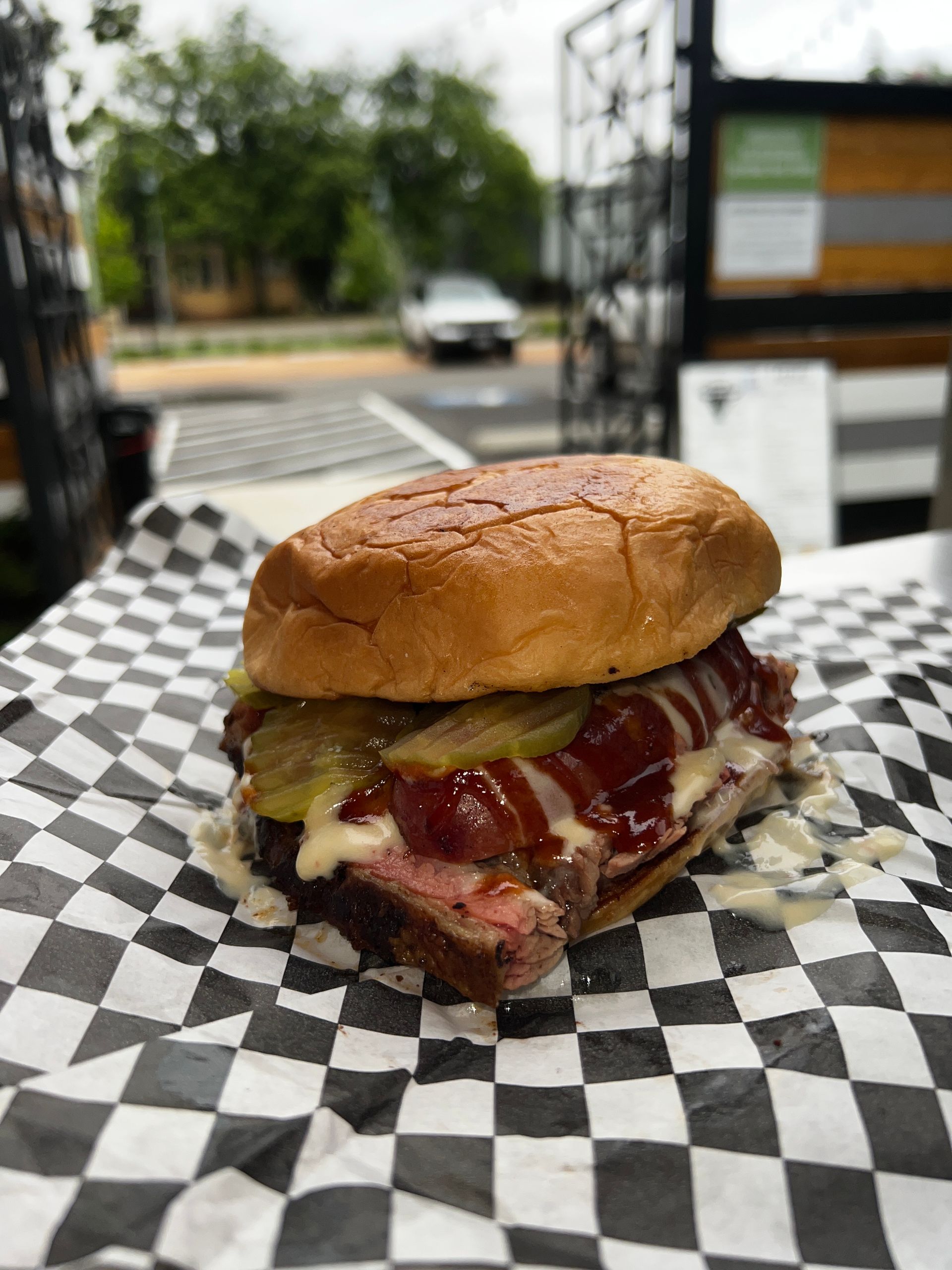A sandwich is sitting on a checkered paper on a table.