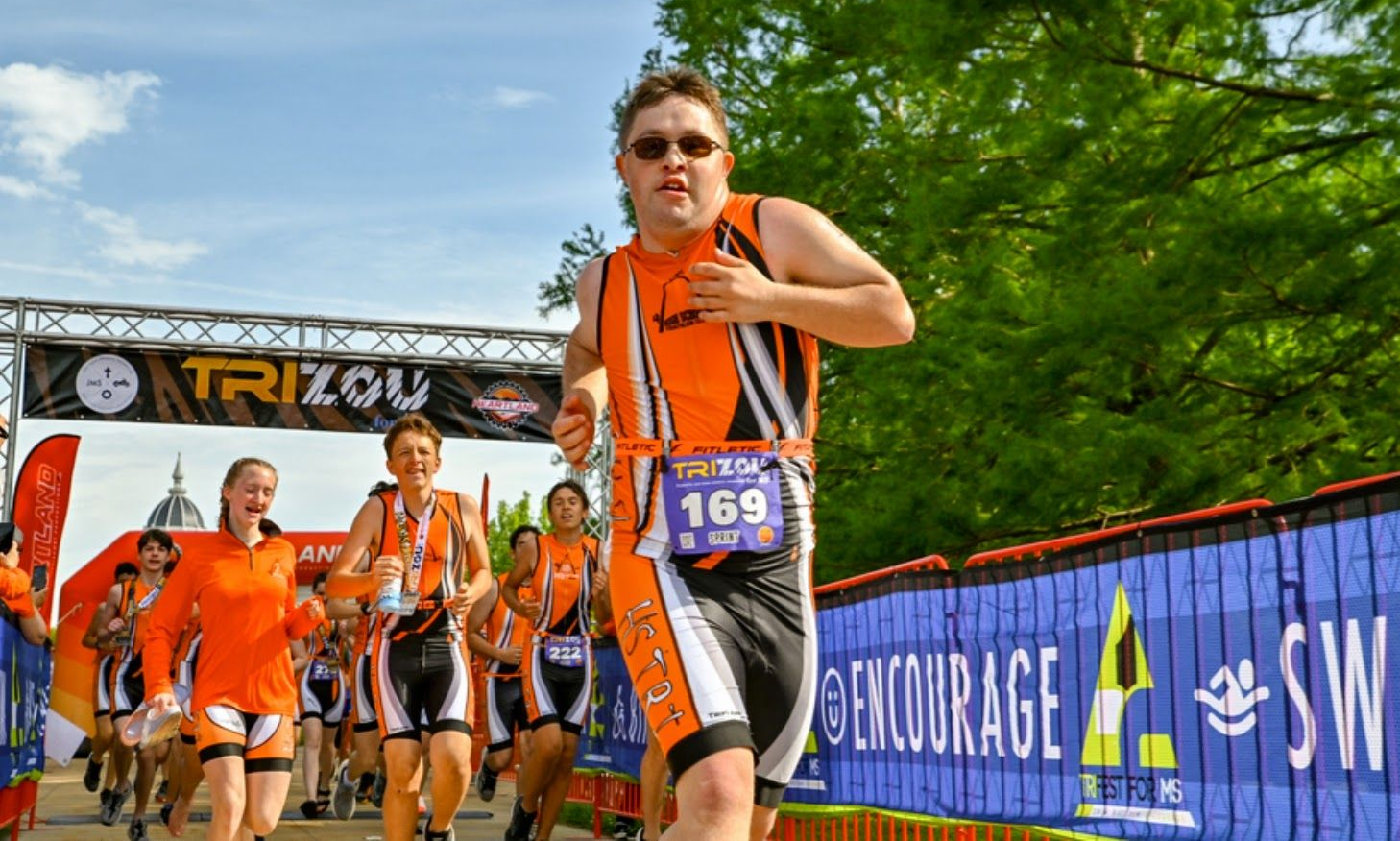 Young man with Down syndrome runs across the finish line after completing a triathlon