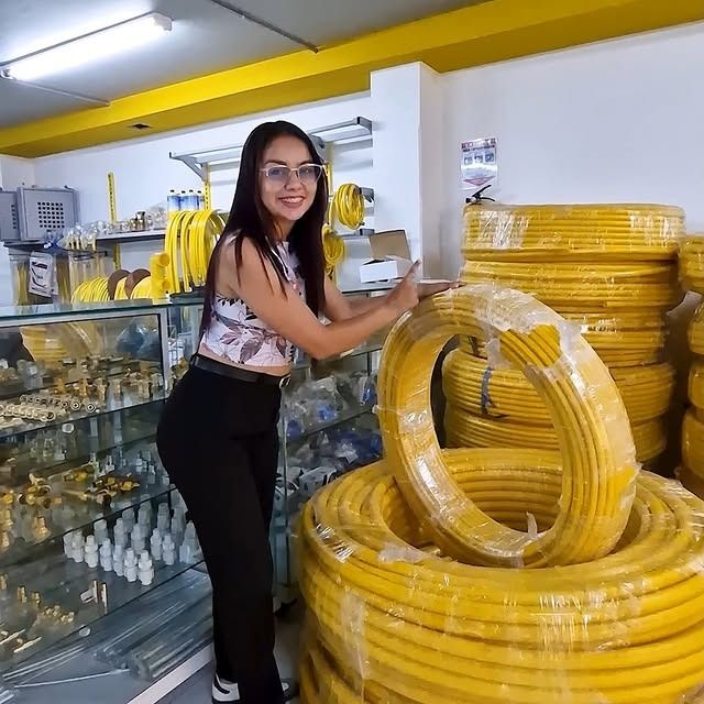 Una mujer en una tienda se apoya en un tubo amarillo. La tienda está muy iluminada con detalles amarillos.