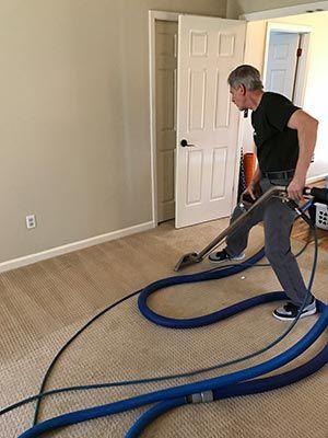 A man is using a vacuum cleaner to clean a carpet in a room.