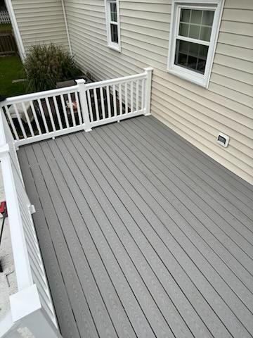 Gray composite deck with white railing, attached to a beige house.