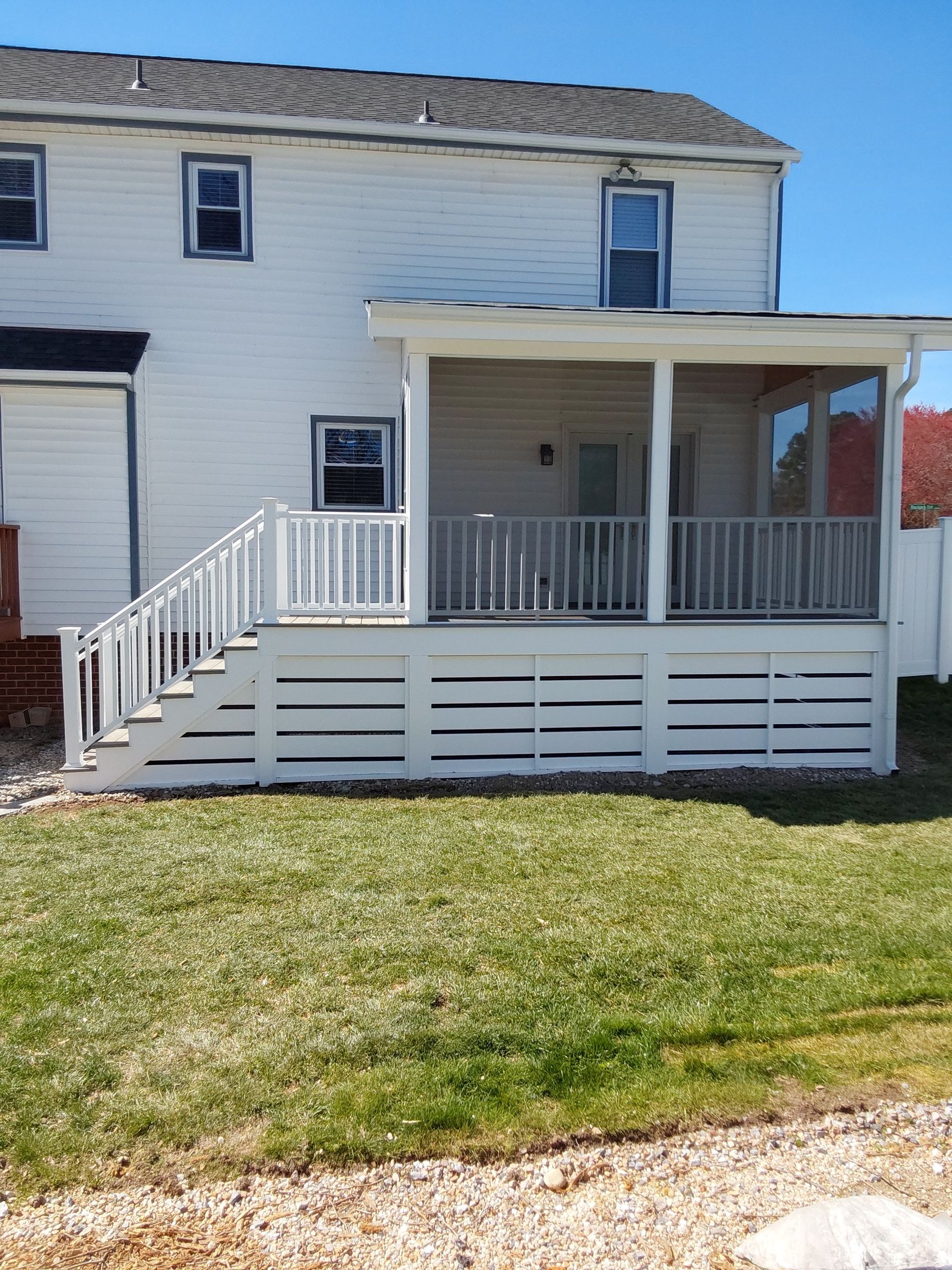 White house with a screened-in porch and steps leading to the yard, light green grass.