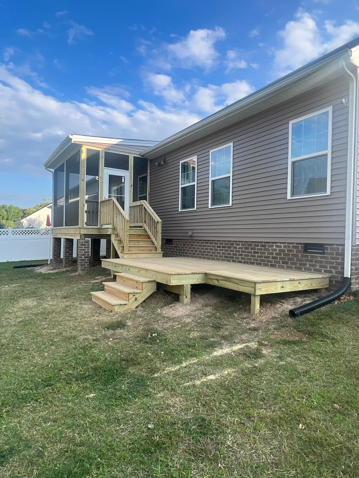 A wooden deck with steps leading to a screened porch, attached to a brown-sided house.