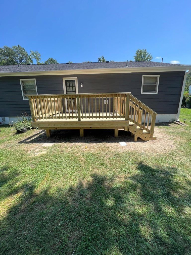 Newly built wooden deck with stairs attached to the back of a house; sunny day.