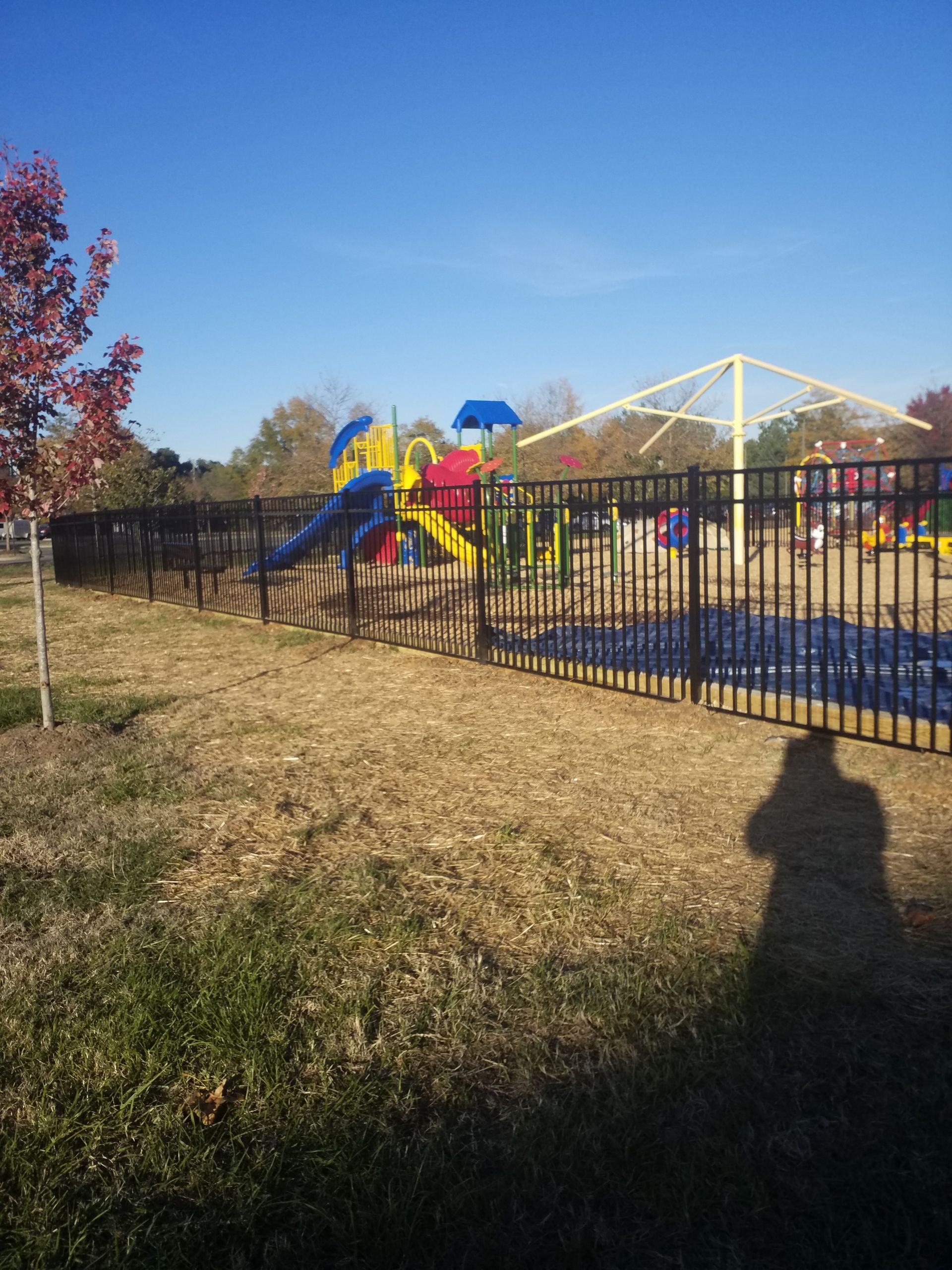 Playground behind a black fence on a sunny day.