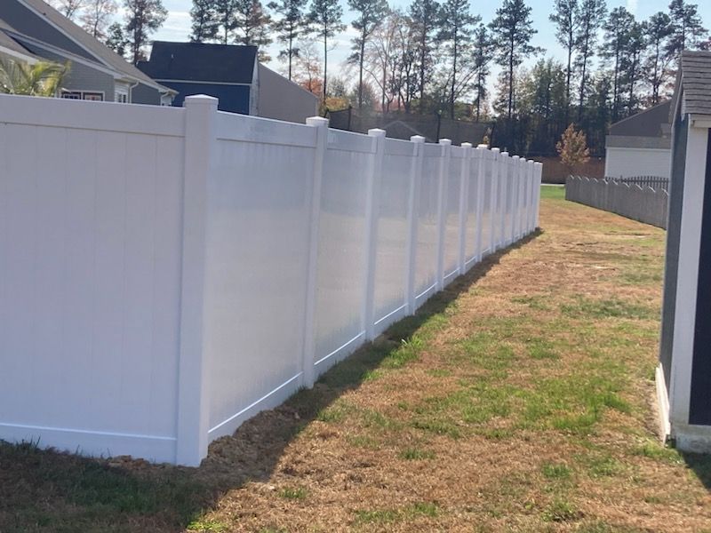 White vinyl privacy fence in a residential backyard.