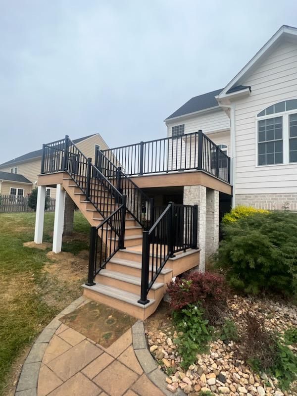 Deck with black railings and stairs leading to a house with a white exterior.
