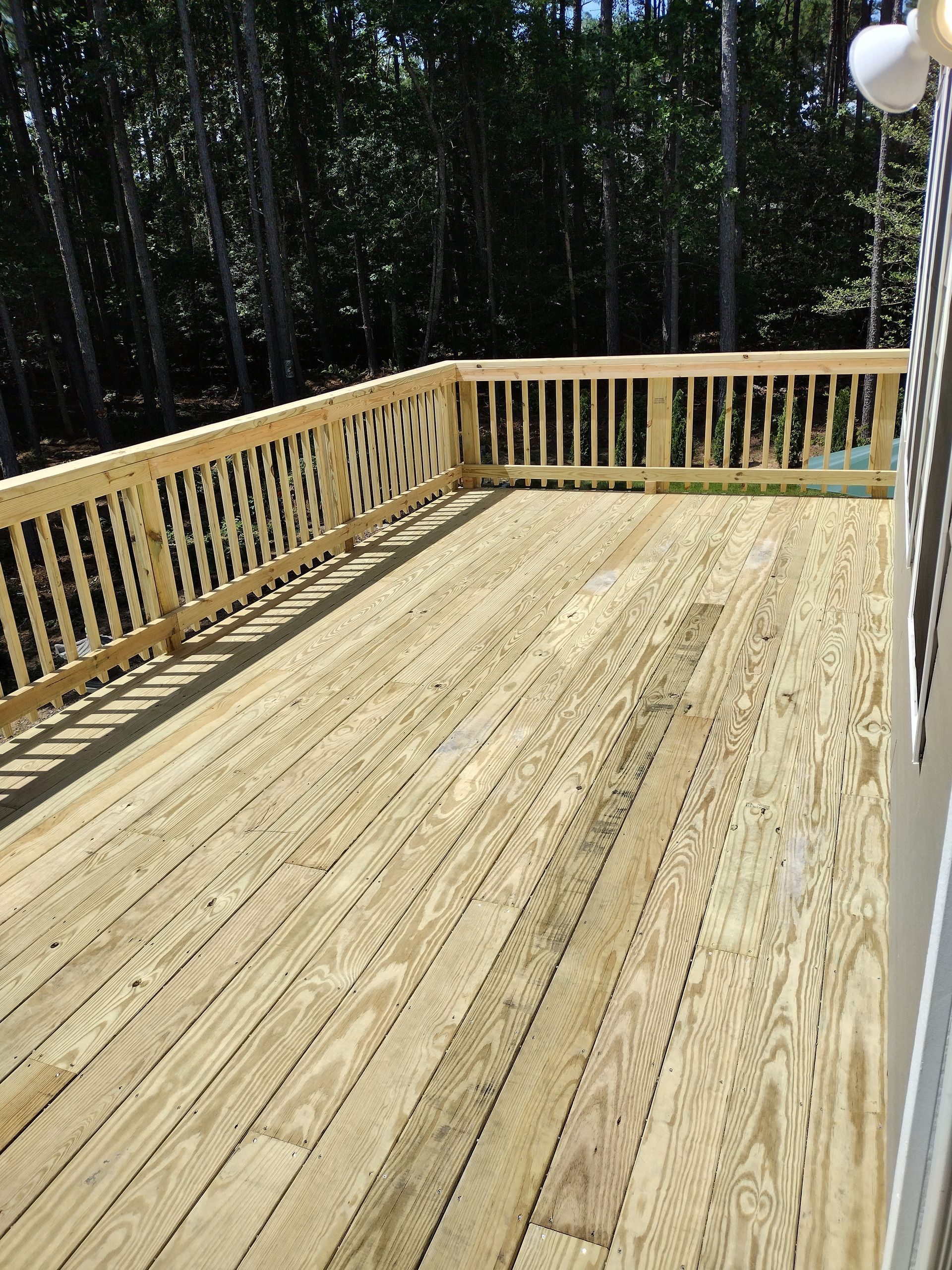 Wooden deck with railing, overlooking a forest.