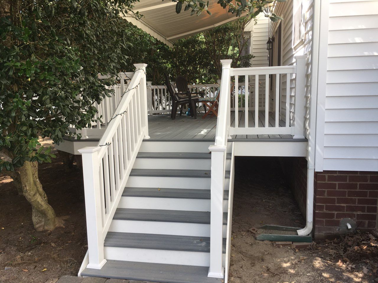 White deck and stairs with gray treads, leading up to a deck covered by a canopy.