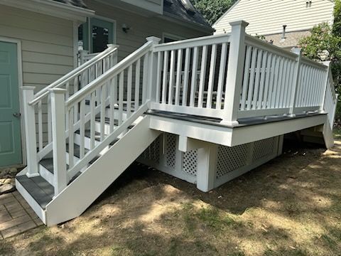 White deck with stairs, railings, and latticework skirting, attached to a light-colored house.