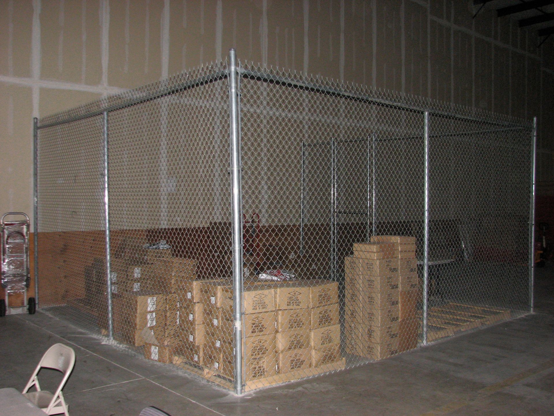Chain-link fence encloses boxes in a warehouse.