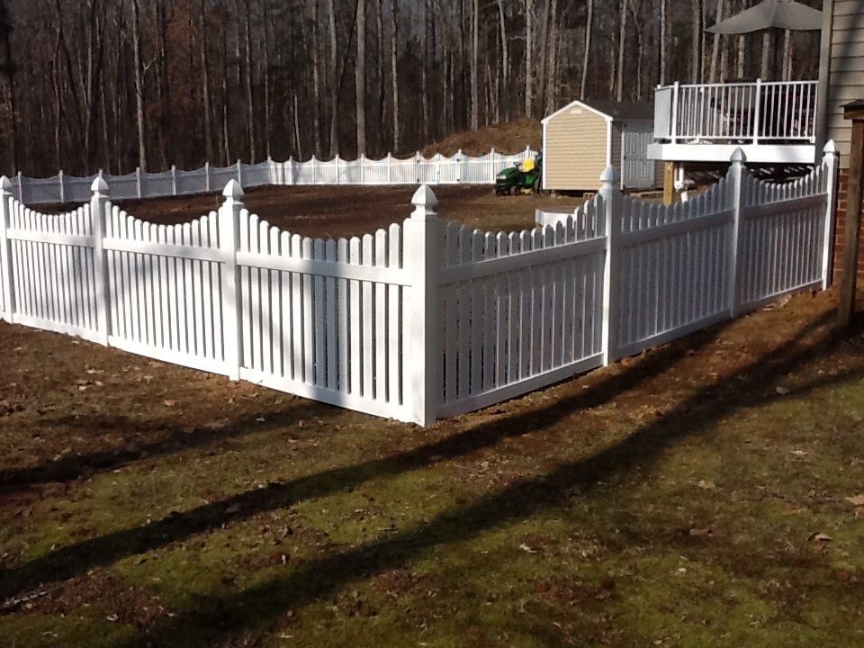 White picket fence surrounds a backyard, with a shed and deck visible in the background.