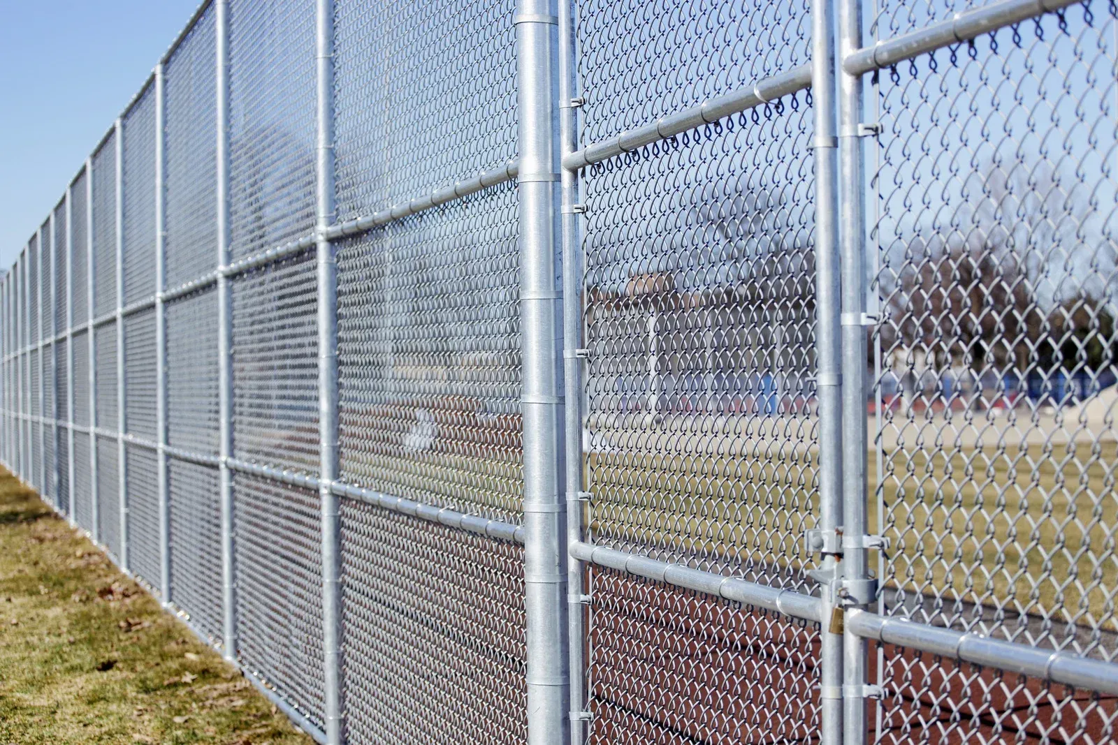 A chain link fence is surrounding a baseball field.