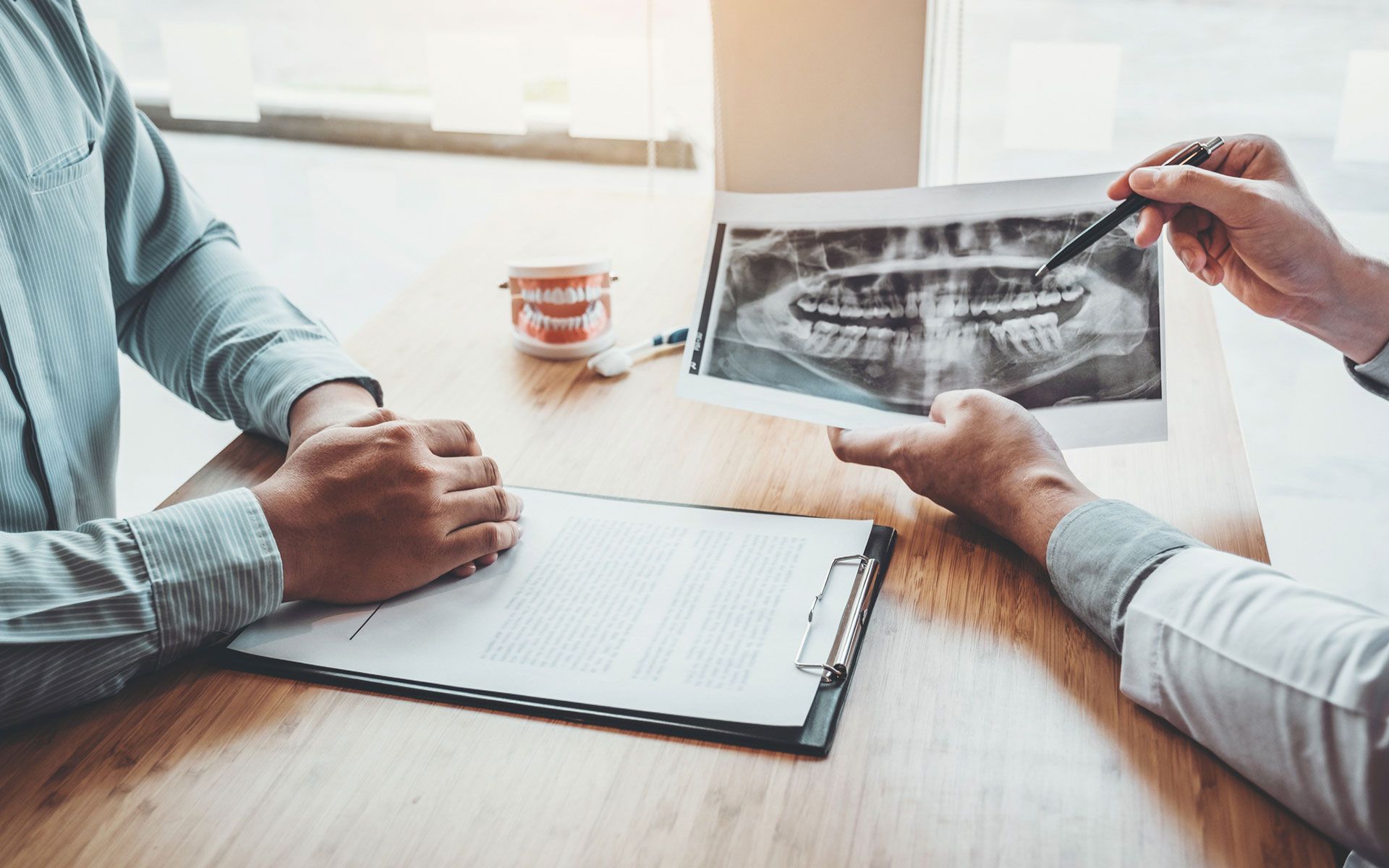 Two people are sitting at a table looking at an x-ray of their teeth.