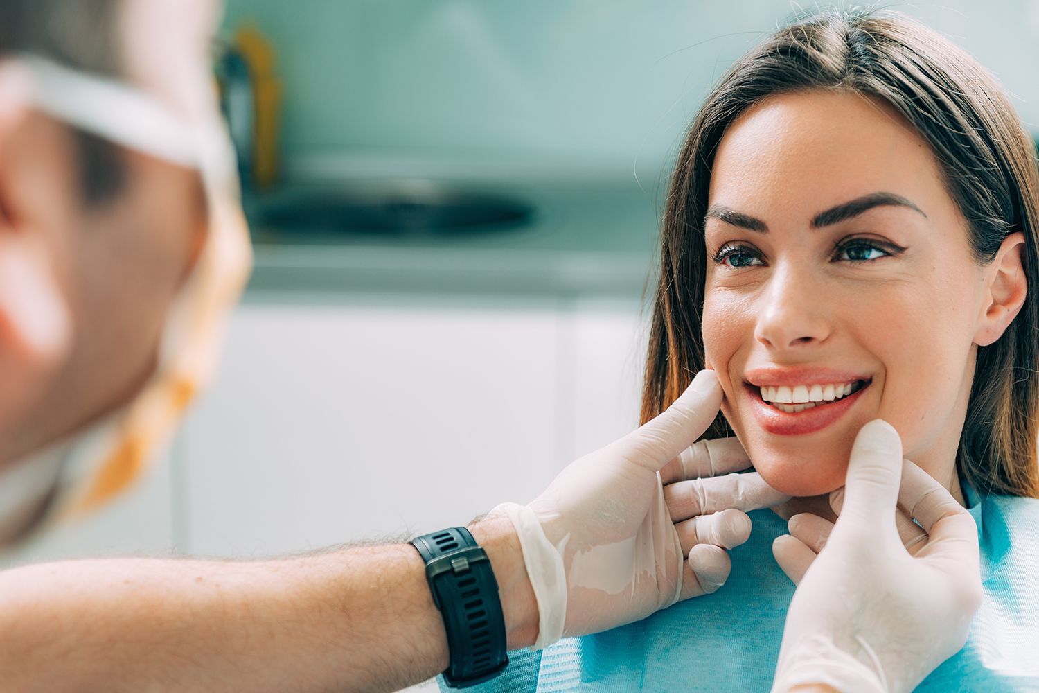 A dentist is contemplating the cosmetic dentistry results of a smiling, beautiful patient.