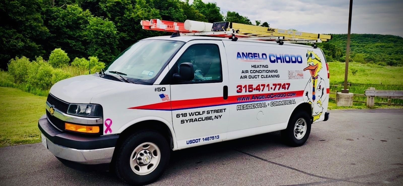 A white van with a ladder on top of it is parked on the side of the road.