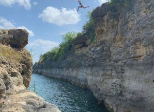 A person is jumping off a cliff into a body of water.