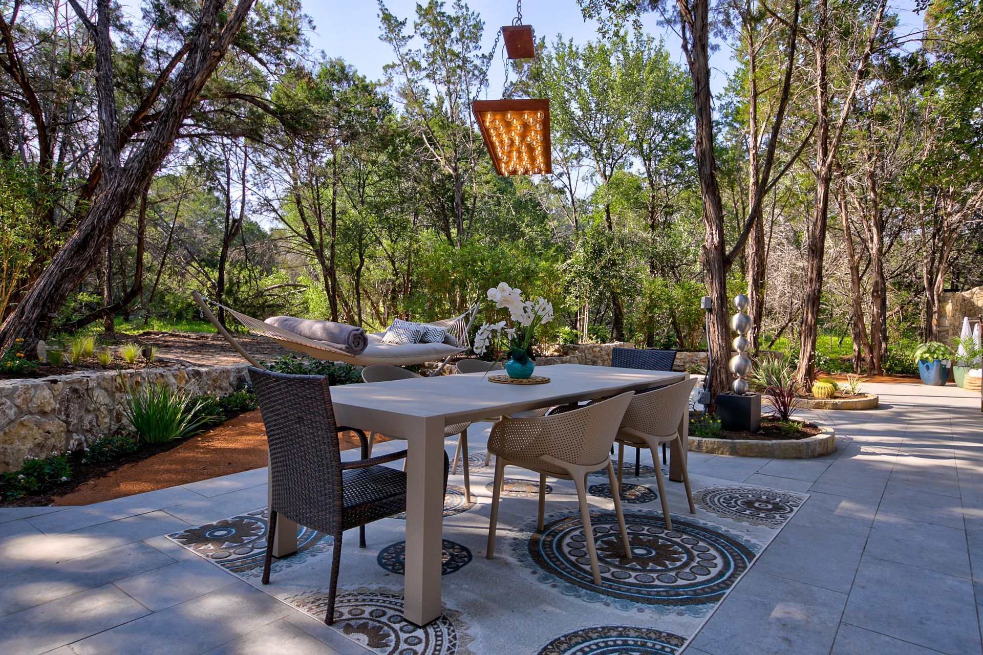 A patio with a table and chairs in the middle of a forest.