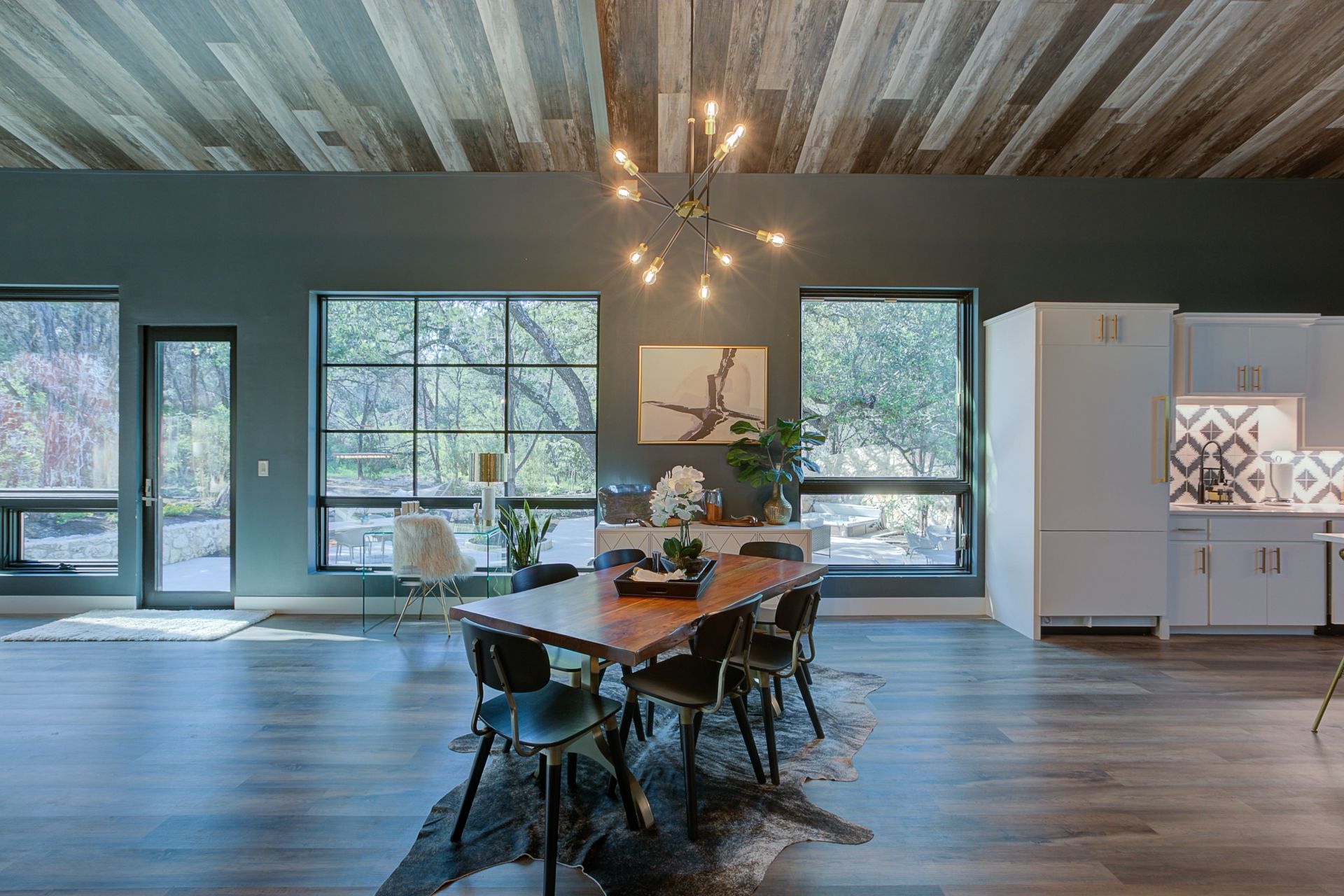 A dining room with a wooden table and chairs and a chandelier.