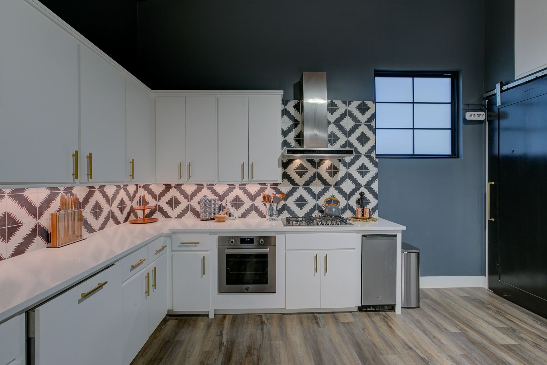 A kitchen with white cabinets , a stove , a refrigerator , and a window.