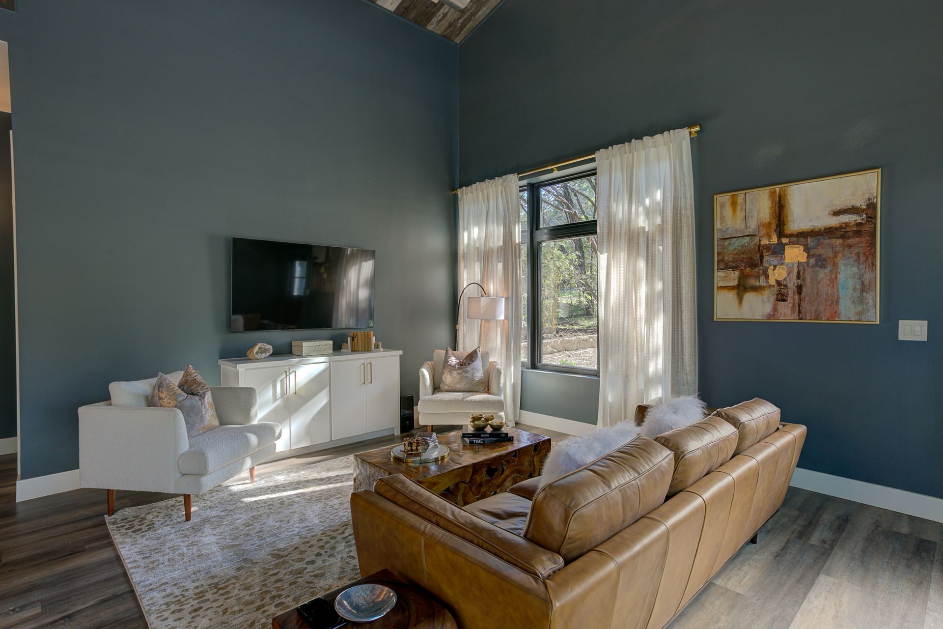 A living room with a couch , chairs , and a flat screen tv.