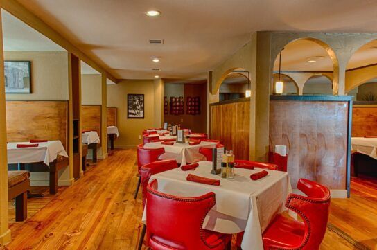 A restaurant with tables and chairs and a wooden floor.