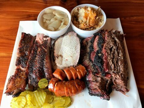 A plate of meat and vegetables on a napkin on a wooden table.