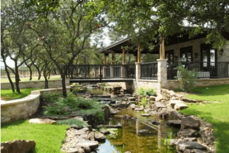 A house with a bridge over a stream in front of it.