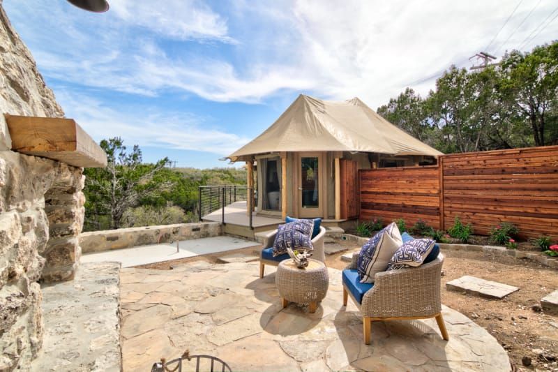A patio with chairs , a table and a tent in the background.