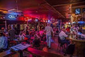 A group of people are sitting at tables in a bar.