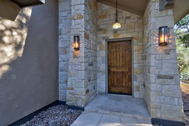 The front door of a house with a wooden door and stone walls.