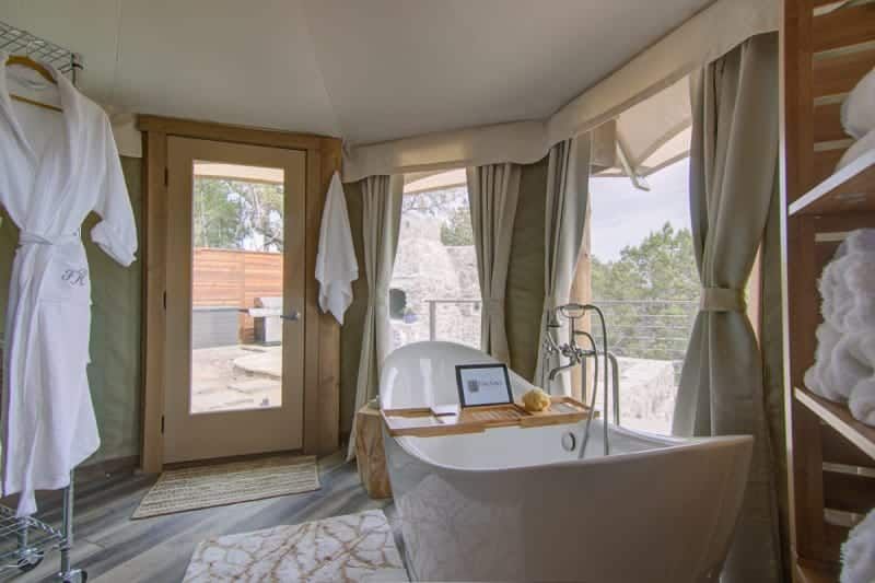 A bathroom with a bathtub and a laptop on a tray.