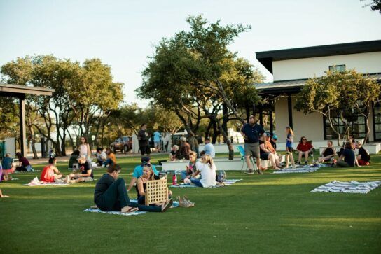 A group of people are sitting on the grass in a park.