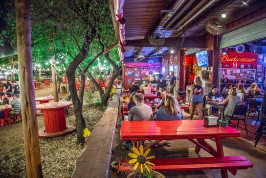 A group of people are sitting at red picnic tables in a restaurant.