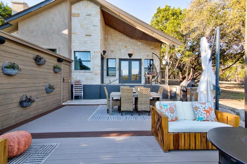 A patio with a couch , table and chairs in front of a house.