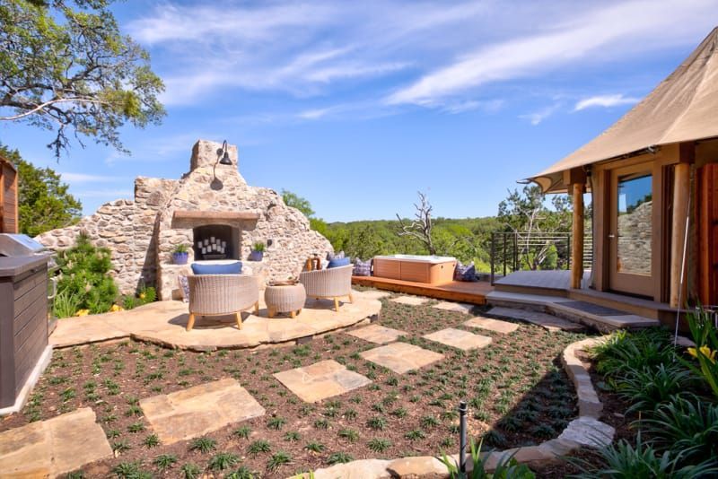 A patio with a fireplace and chairs in front of a house.