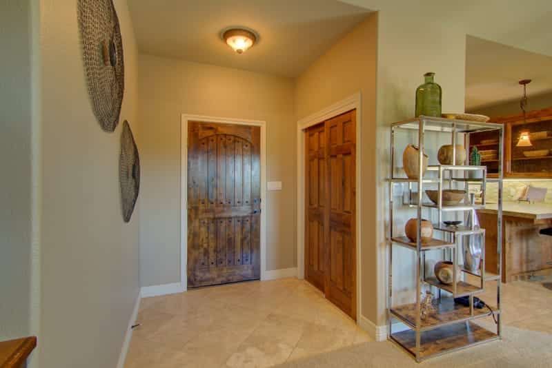 A hallway in a house with a wooden door and a shelf with vases on it.