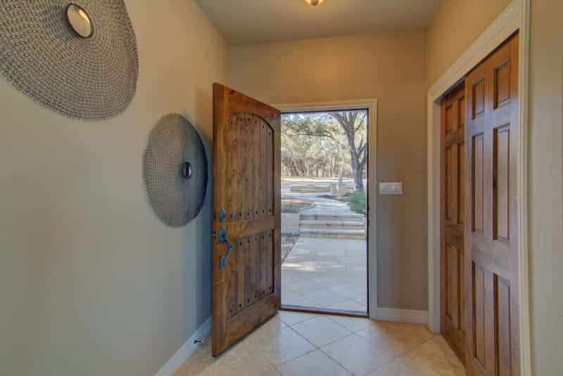 A hallway with a wooden door and a tiled floor.