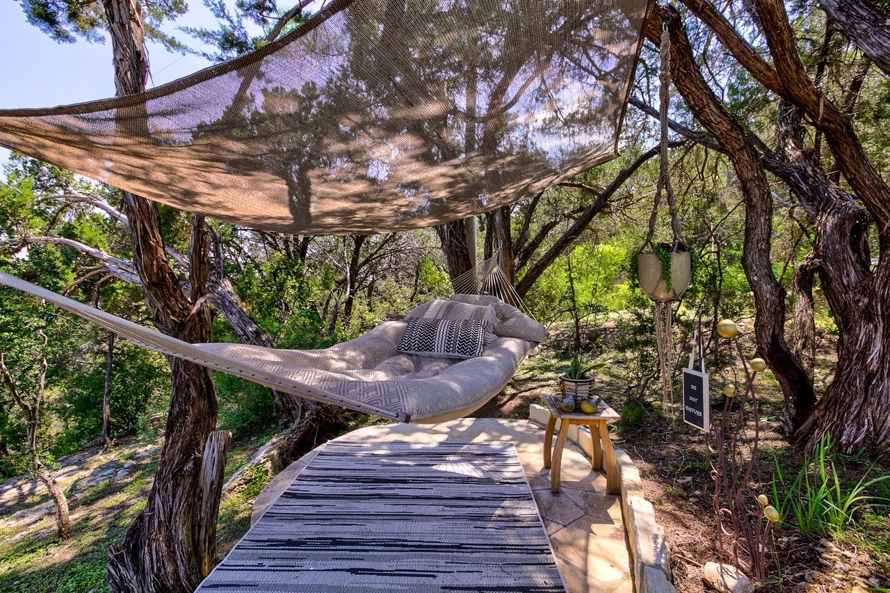 A hammock is hanging over a wooden deck in the woods.