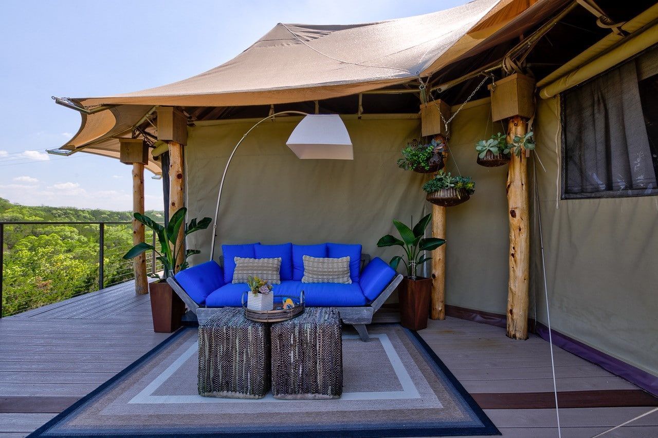 A blue couch is sitting under a tent on a deck.