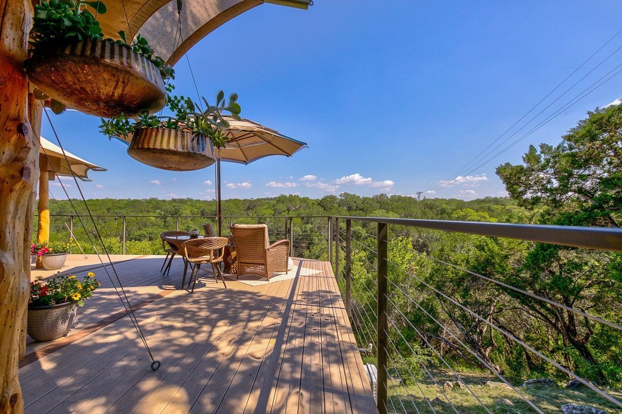 A wooden deck with umbrellas and chairs overlooking a forest.