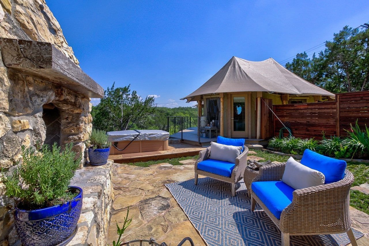 A patio with a tent , chairs , a fireplace and a hot tub.