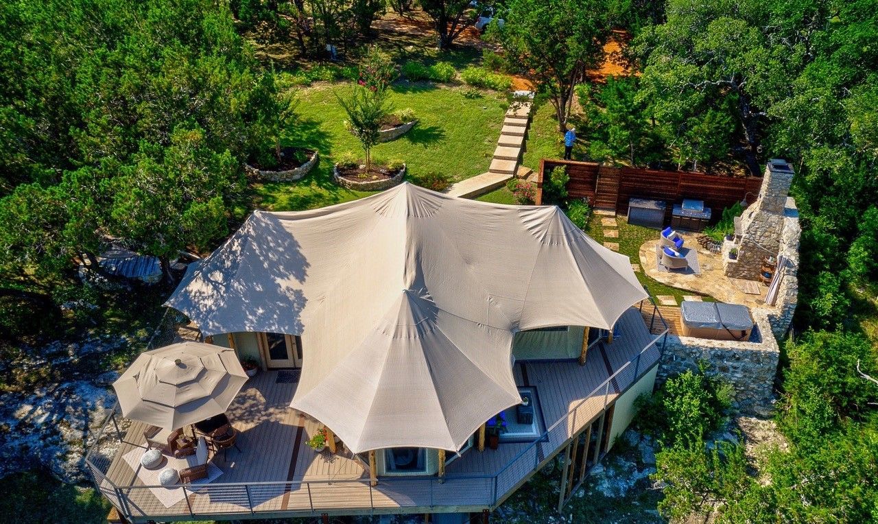 An aerial view of a tent in the middle of a forest.