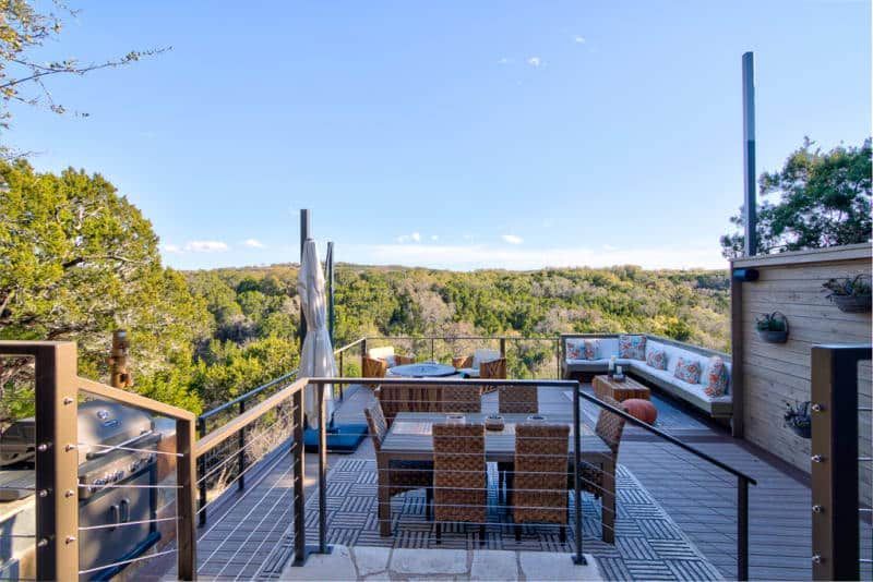 A deck with a table and chairs and a view of a forest.