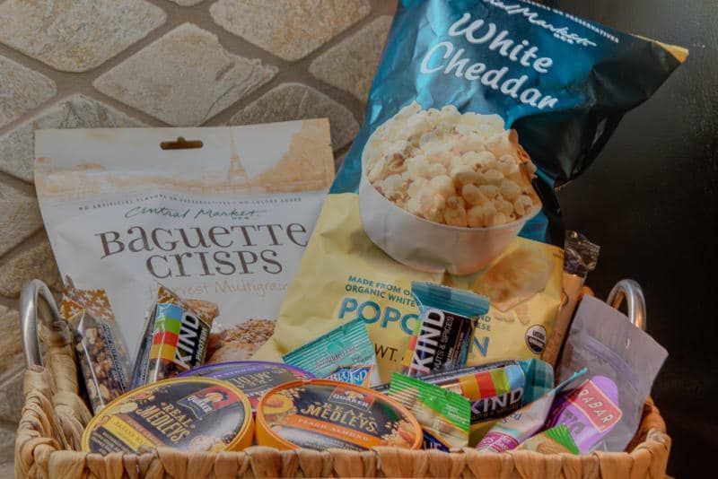 A basket filled with snacks including a bag of white cheddar popcorn.