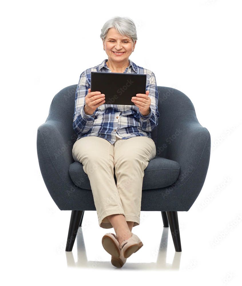 An elderly woman is sitting in a chair holding a tablet