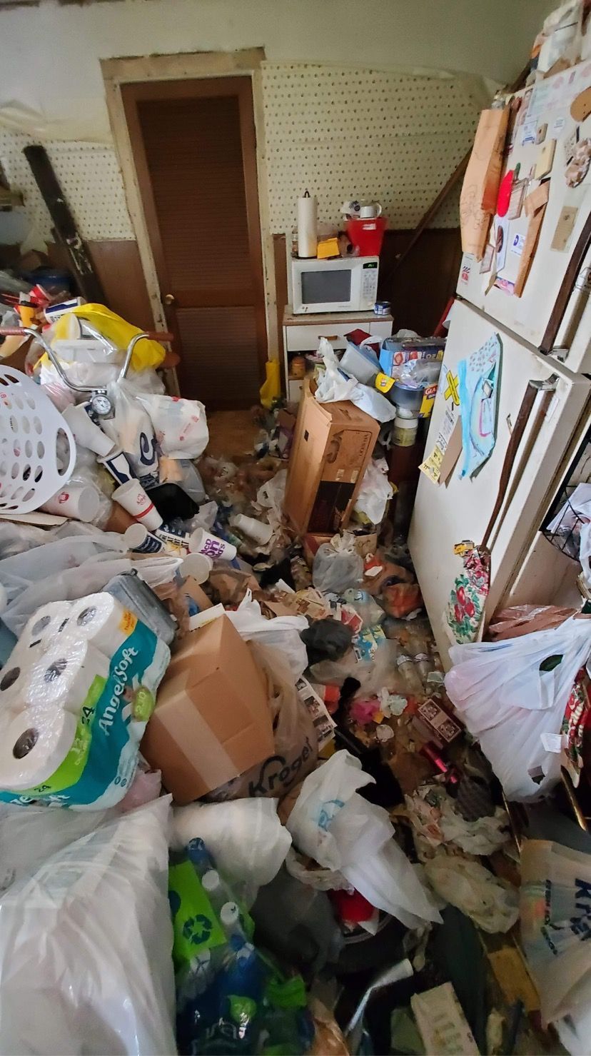 Cluttered, overflowing storage room with boxes, bags, and supplies piled across the floor and shelves