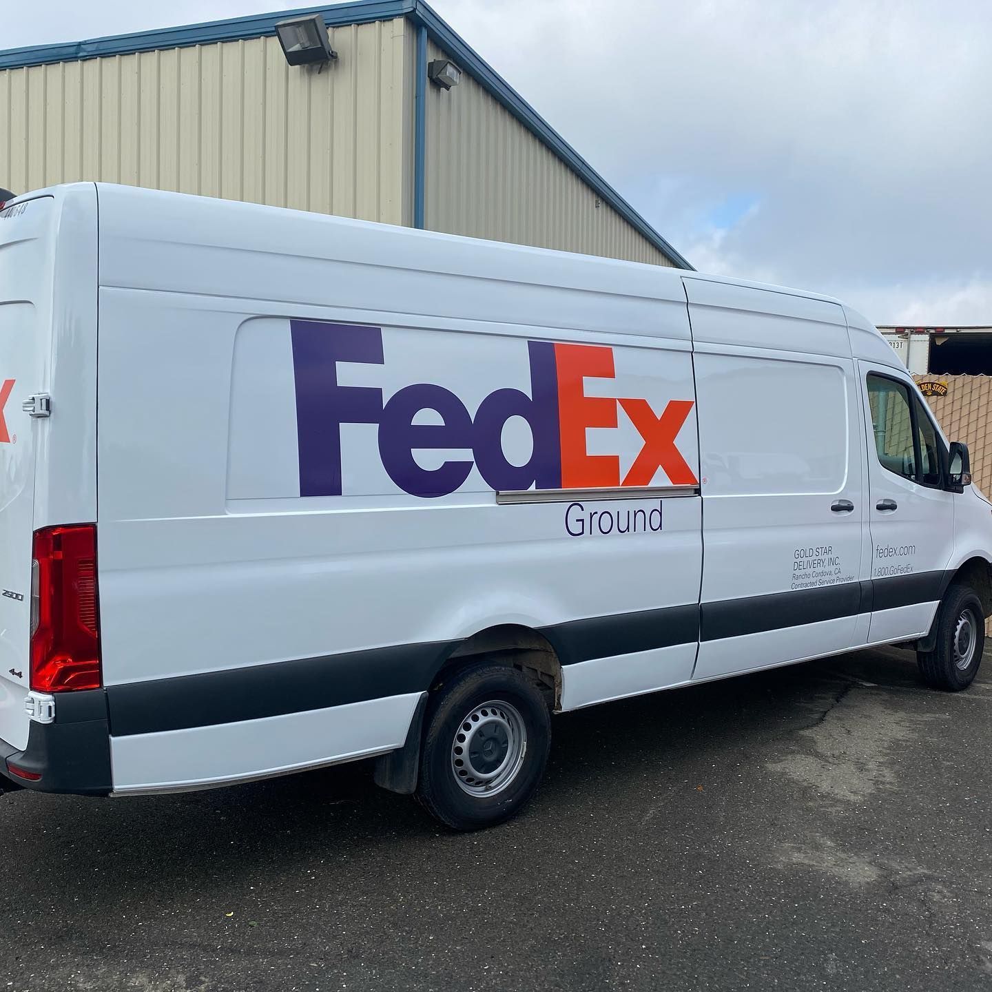 A white fedex van is parked in front of a building